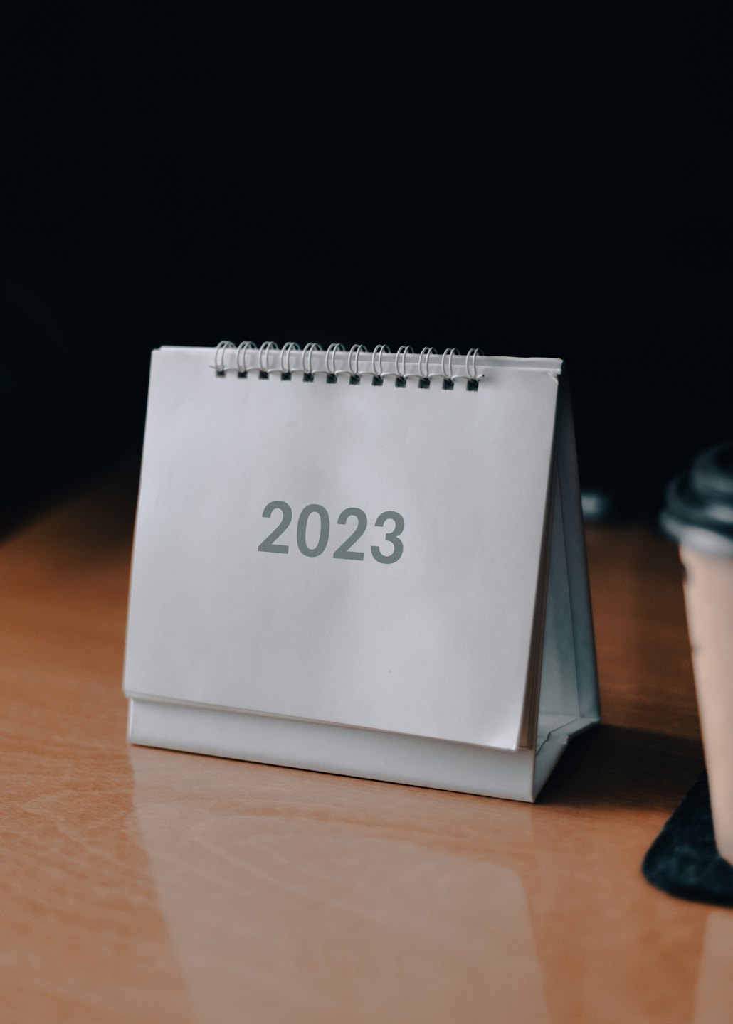 Calendario a spirale del 2023 su una scrivania di legno.